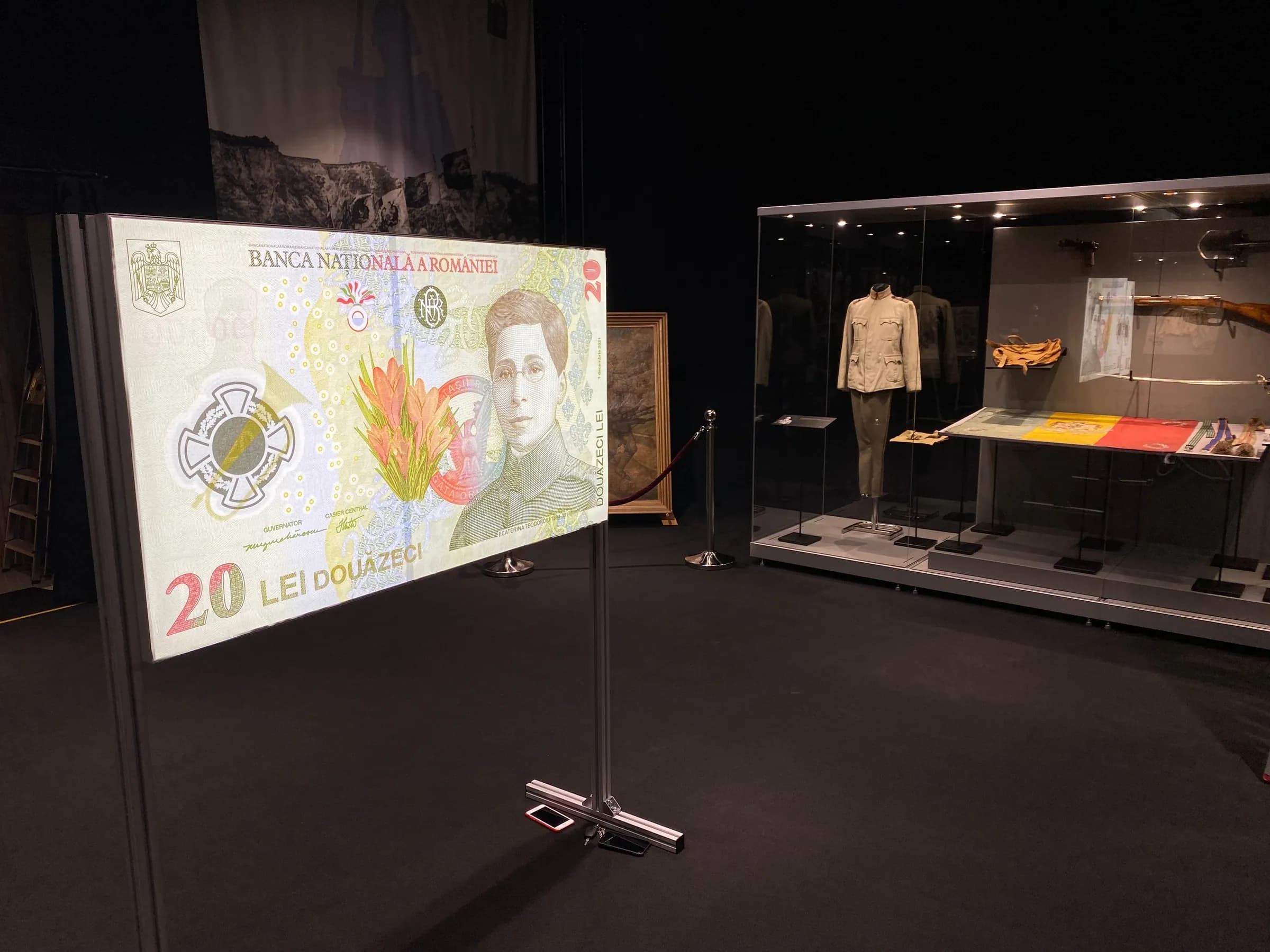 Sala expoziției temporare: o bancnotă de 20 de lei mărită, în fața vitrinelor cu obiecte de epocă